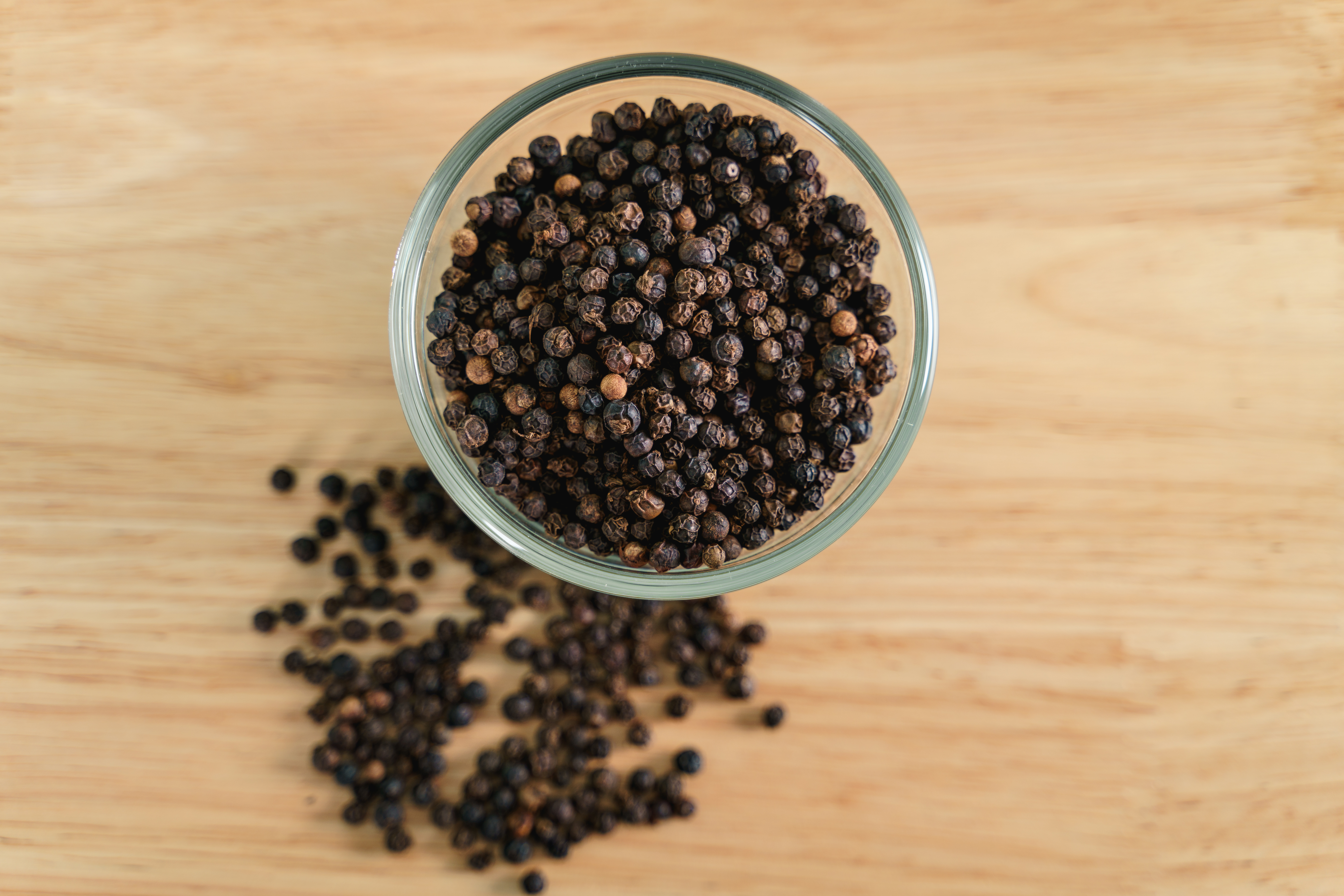 Black peppercorns scattered on rustic surface